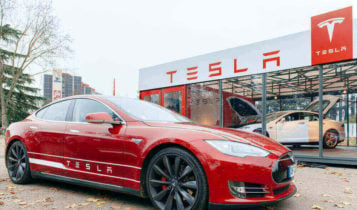 A Tesla Model S parked in front of a Tesla dealership