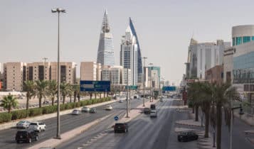a view of a city in saudi arabia with buildings on the background and cars on the road