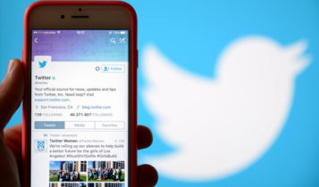 Phone showing the twitter app as the twitter logo is shown on the background