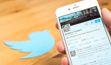 Donald Trump's twitter profile is shown on a phone screen with the twitter logo on left side