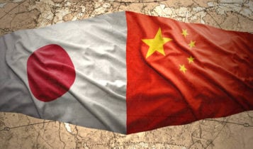 japan and china flags side by side on a brown background