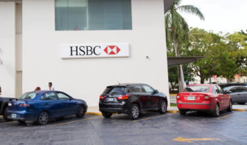 HSBC logo attached to a wall with 3 cars parked on a parking space