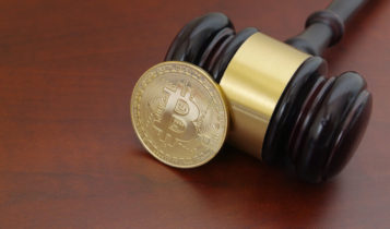 bitcoin in a form of coin leaning on a wooden gaven on wooden surface