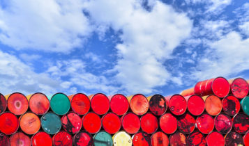 oil barrels stacked on top of each other with a blue sky as a background